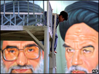 Boy plays in front of portraits of Ayatollah Khamenei (l) and   Ayatollah Khomeini (r)